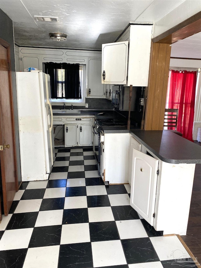 kitchen with a peninsula, dark floors, visible vents, and white refrigerator with ice dispenser