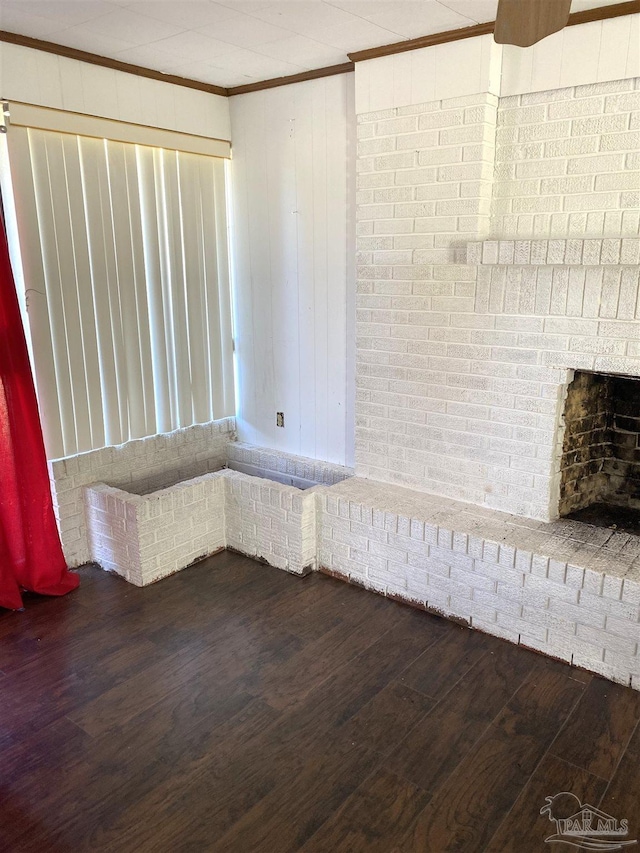 spare room featuring brick wall, dark wood-type flooring, and crown molding