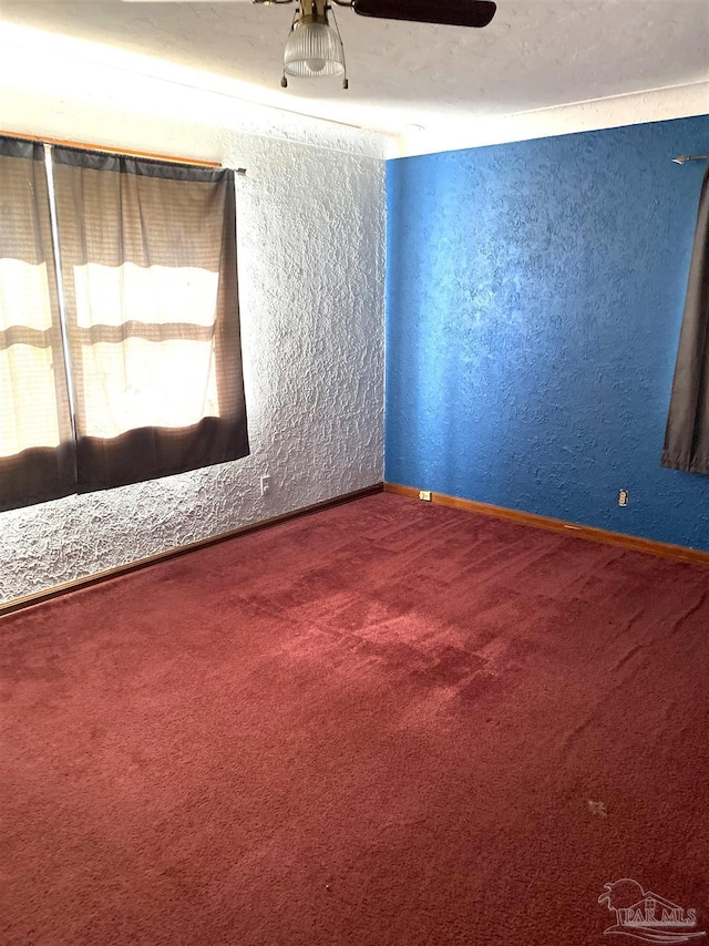 empty room featuring a ceiling fan, carpet flooring, and a textured wall