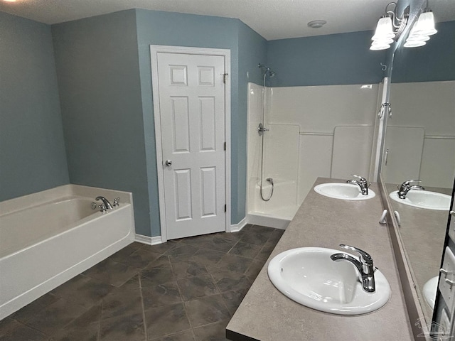 bathroom with a textured ceiling, vanity, and separate shower and tub