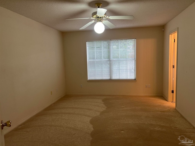 empty room featuring light carpet, a textured ceiling, and ceiling fan