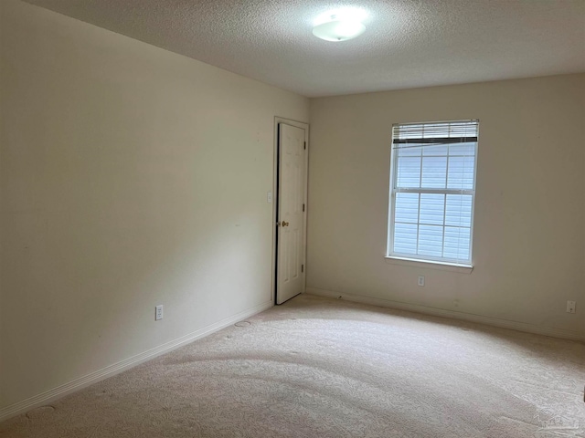 carpeted empty room with a textured ceiling