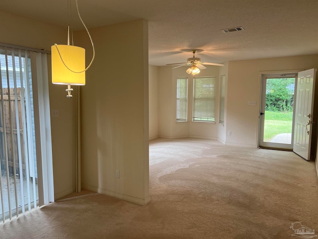 unfurnished room featuring a textured ceiling, ceiling fan, and light carpet