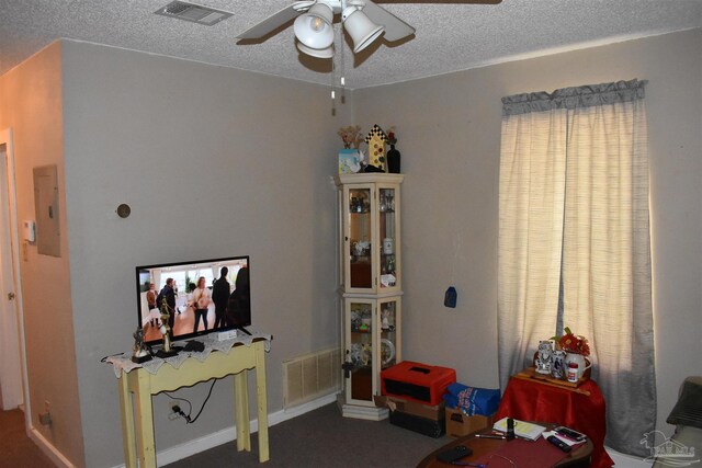 interior space with electric panel, ceiling fan, a textured ceiling, and dark carpet