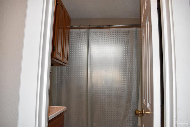 bathroom featuring a shower with curtain, a textured ceiling, and vanity