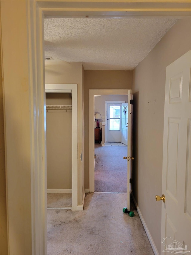 hall featuring a textured ceiling and light carpet