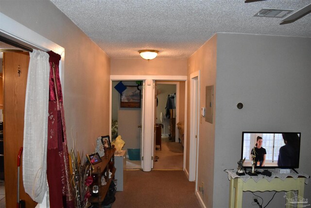 hallway featuring electric panel, a textured ceiling, and light colored carpet