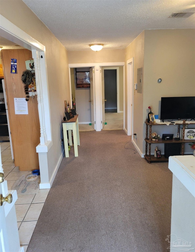 corridor featuring light carpet, electric panel, and a textured ceiling