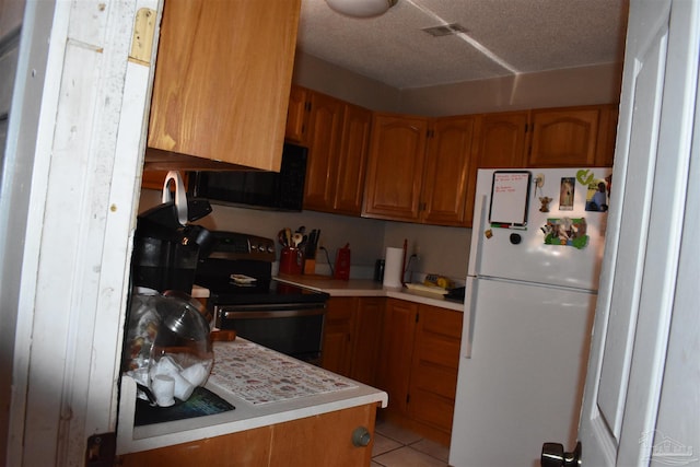 kitchen featuring a textured ceiling, black appliances, and light tile patterned floors