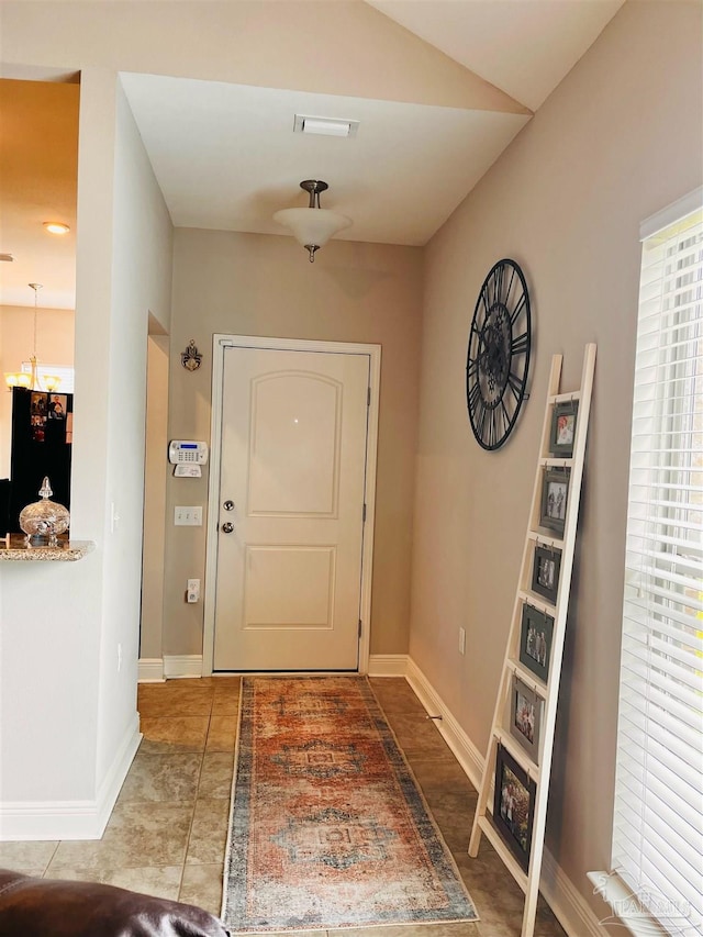 tiled entryway featuring a notable chandelier