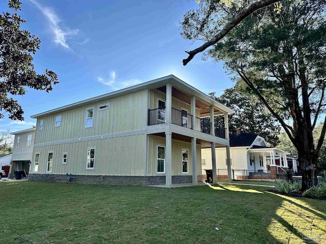 back of property with a yard and a balcony