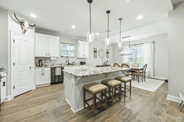 1567 Sawyers Ridge Cv, Cantonment, FL 32533 - kitchen featuring stainless steel dishwasher, a kitchen breakfast bar, a center island, white cabinetry, and healthy amount of natural light
