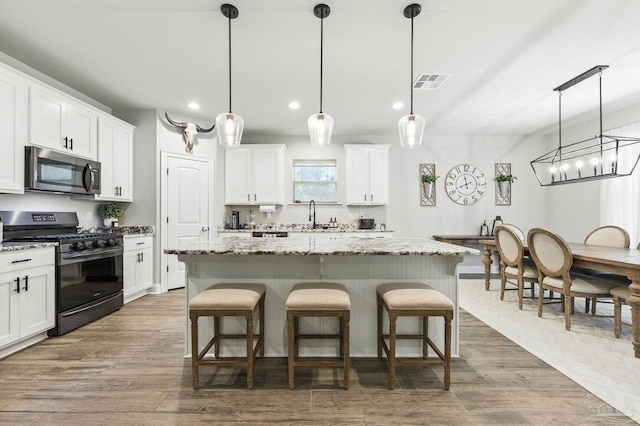 1567 Sawyers Ridge Cv, Cantonment, FL 32533 - kitchen featuring stainless steel microwave, gas range oven, a center island, dark wood-type flooring, and recessed lighting