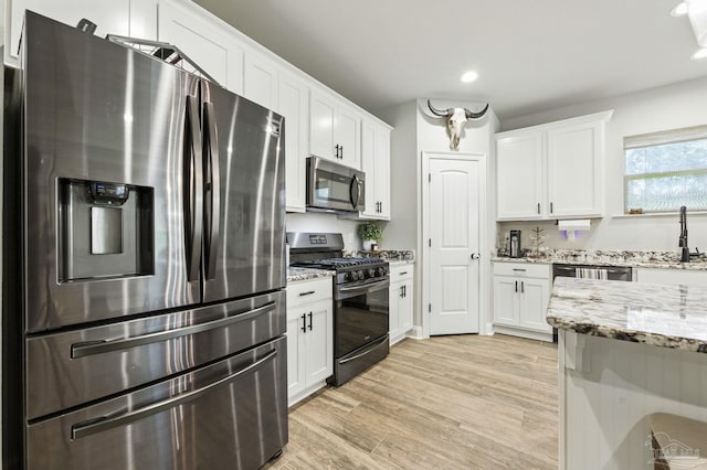 1567 Sawyers Ridge Cv, Cantonment, FL 32533 - kitchen featuring appliances with stainless steel finishes, white cabinets, recessed lighting, light stone countertops, and light wood-type flooring