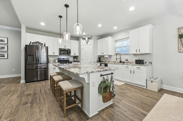 1567 Sawyers Ridge Cv, Cantonment, FL 32533 - kitchen with appliances with stainless steel finishes, a kitchen island, white cabinets, a breakfast bar, and dark wood-style flooring