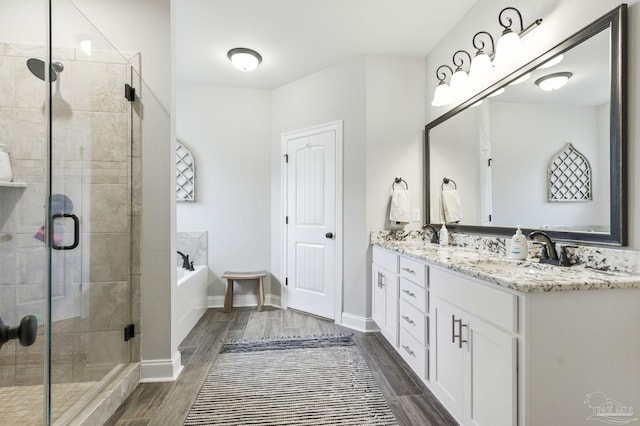 1567 Sawyers Ridge Cv, Cantonment, FL 32533 - bathroom featuring double vanity, a garden tub, a shower stall, and wood finished floors
