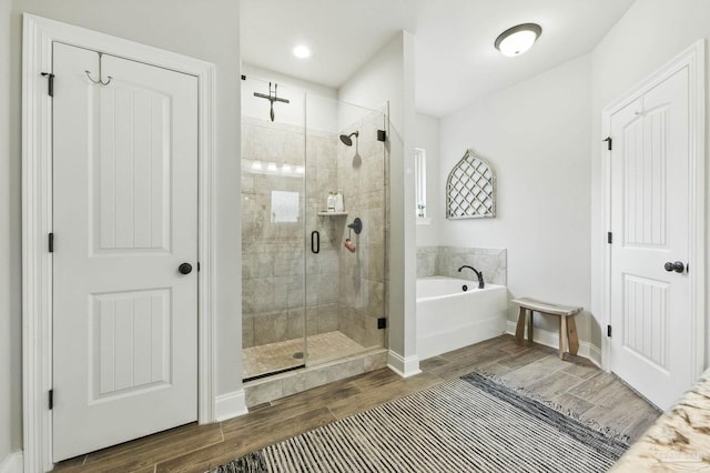 1567 Sawyers Ridge Cv, Cantonment, FL 32533 - bathroom featuring a garden tub, a shower stall, and wood finished floors