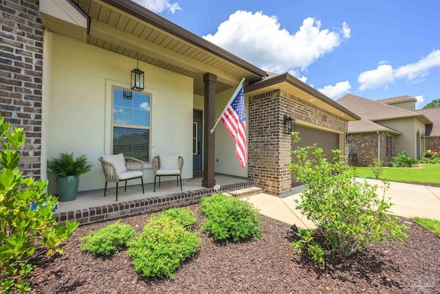 1567 Sawyers Ridge Cv, Cantonment, FL 32533 - view of exterior entry featuring a porch, brick siding, a garage, driveway, and stucco siding