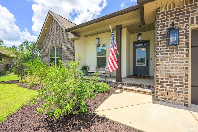 1567 Sawyers Ridge Cv, Cantonment, FL 32533 - doorway to property featuring a porch, brick siding, and stucco siding