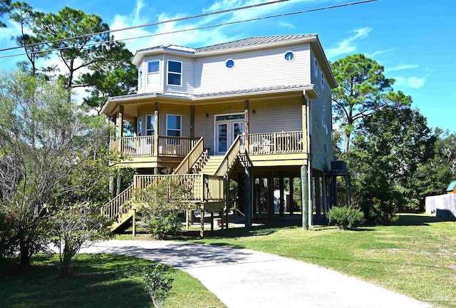 coastal home featuring covered porch and a front lawn