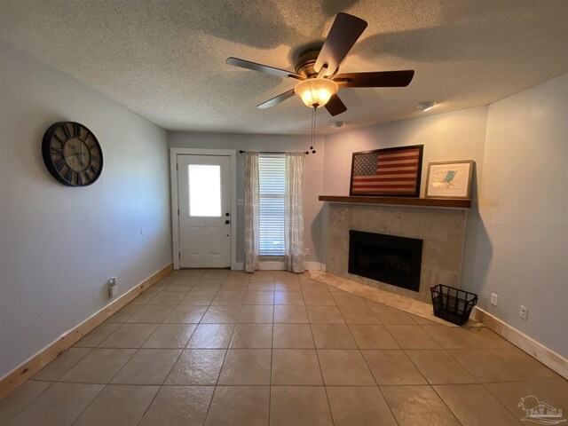 tiled living room with a textured ceiling, a tiled fireplace, and ceiling fan