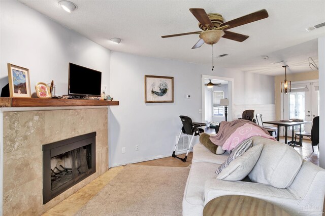 living room featuring ceiling fan, a textured ceiling, and a fireplace