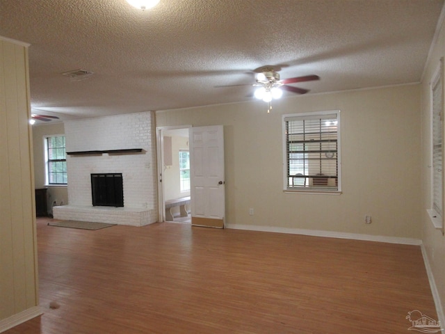 5078 Babb Ln, Pace, FL 32571 - unfurnished living room featuring ceiling fan, wood finished floors, a textured ceiling, and a brick fireplace