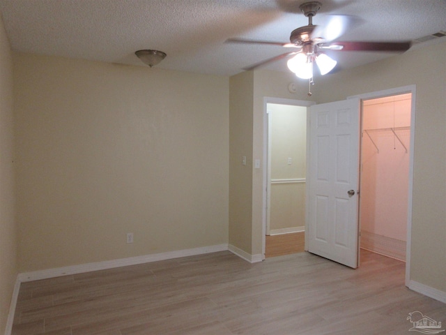 5078 Babb Ln, Pace, FL 32571 - unfurnished bedroom with light wood-style floors, a textured ceiling, a closet, a walk in closet, and a ceiling fan