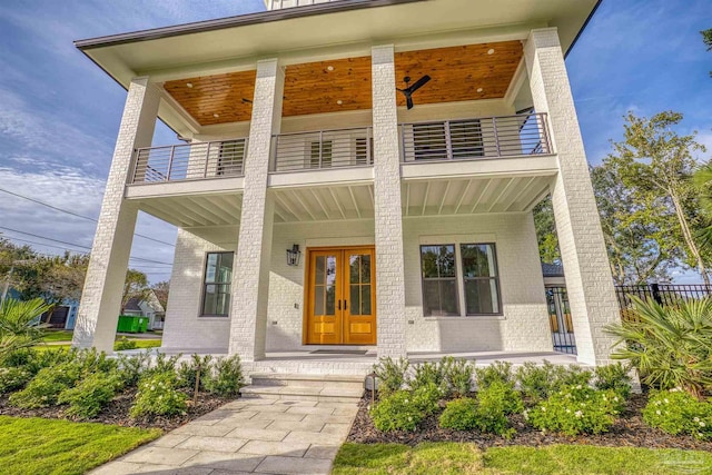 entrance to property with a balcony, covered porch, and french doors