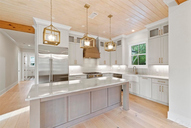 kitchen with stainless steel appliances, a kitchen island, white cabinets, and decorative light fixtures