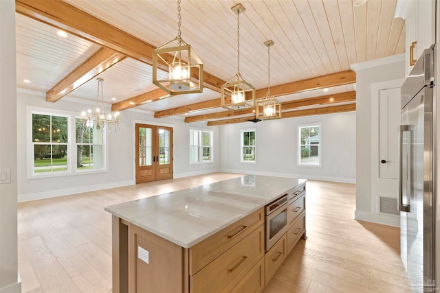 kitchen with light hardwood / wood-style flooring, stainless steel appliances, a kitchen island, decorative light fixtures, and light brown cabinets