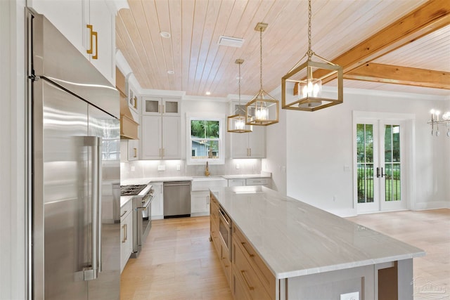 kitchen featuring high quality appliances, white cabinetry, a kitchen island, and hanging light fixtures