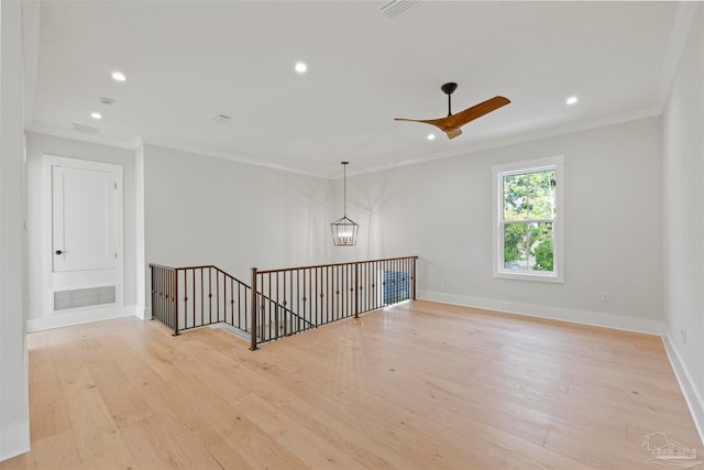 spare room featuring ornamental molding, ceiling fan with notable chandelier, and light hardwood / wood-style flooring