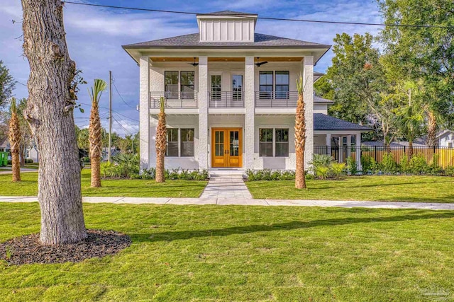 view of front of house featuring french doors, a balcony, ceiling fan, and a front lawn