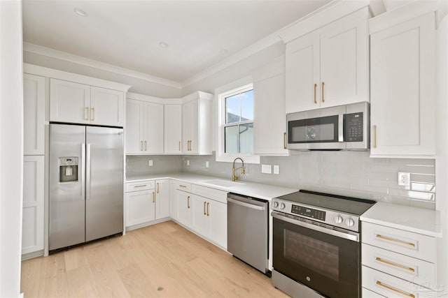 kitchen with appliances with stainless steel finishes, sink, decorative backsplash, and white cabinets