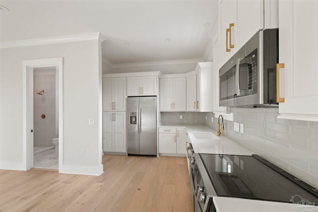 kitchen featuring appliances with stainless steel finishes, sink, white cabinets, and light hardwood / wood-style floors