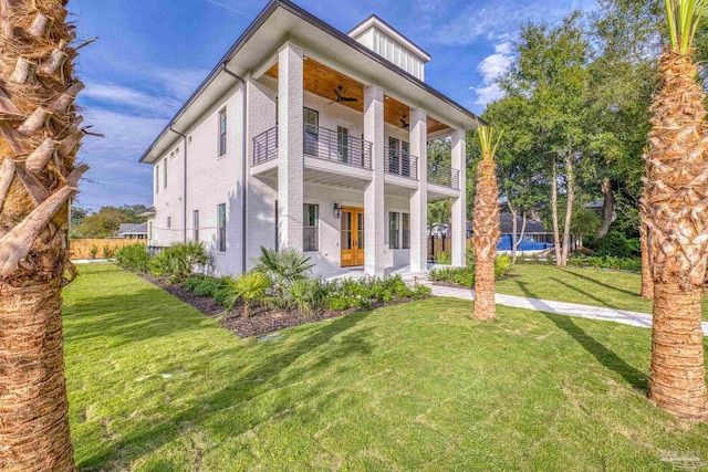 view of front of home featuring ceiling fan, a front lawn, and a balcony