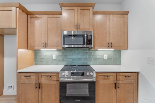 kitchen with backsplash, stainless steel appliances, light brown cabinetry, and light wood-type flooring