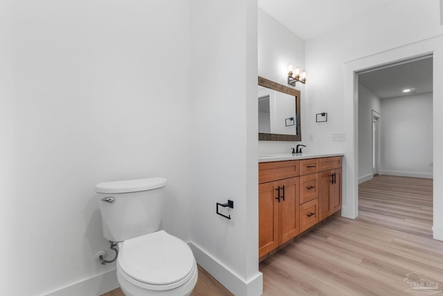 bathroom with toilet, hardwood / wood-style flooring, and vanity