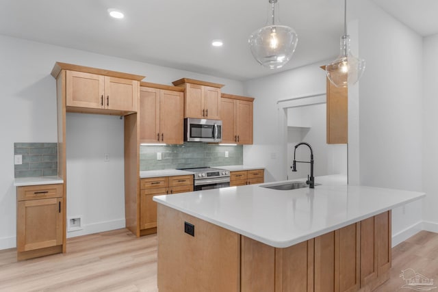 kitchen with tasteful backsplash, sink, light wood-type flooring, stainless steel appliances, and pendant lighting