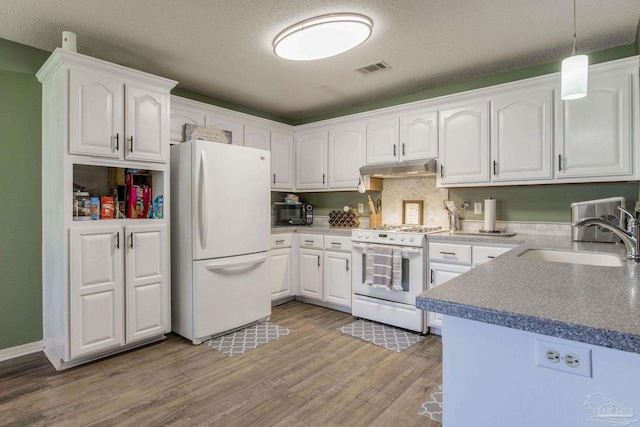 kitchen with hanging light fixtures, sink, light wood-type flooring, white cabinetry, and white appliances