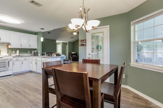 dining space featuring lofted ceiling, a textured ceiling, a notable chandelier, and light wood-type flooring