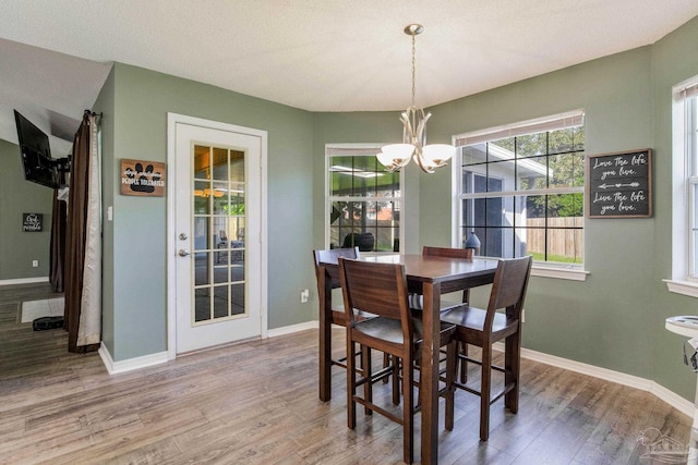 dining space featuring an inviting chandelier, a textured ceiling, and wood-type flooring