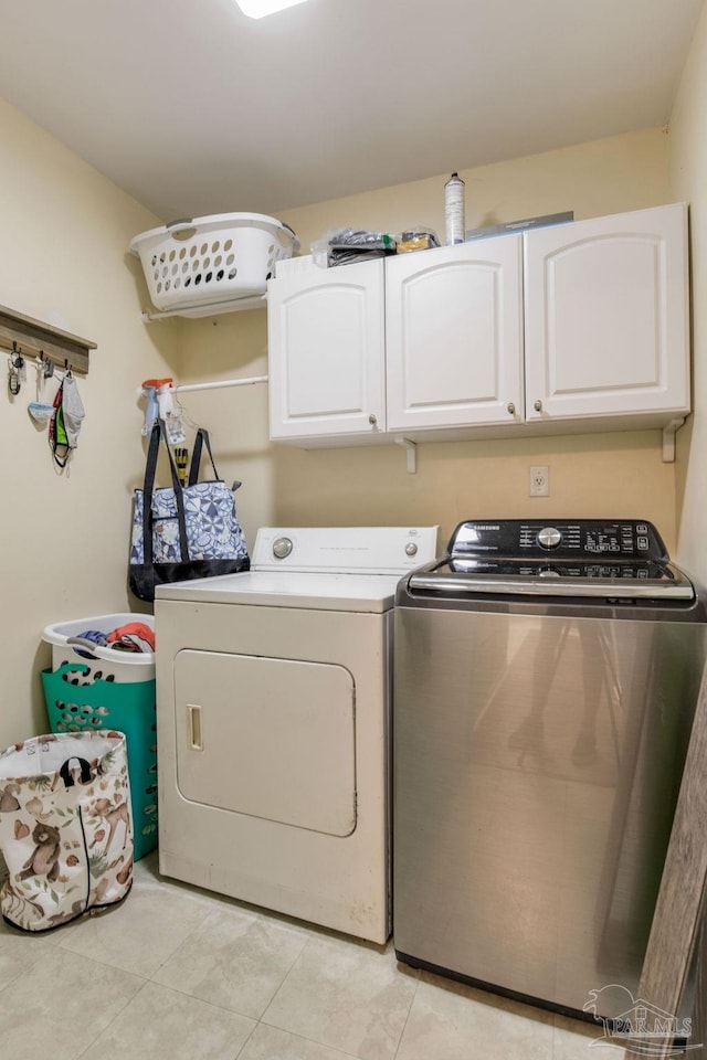 washroom featuring light tile patterned flooring, cabinets, and separate washer and dryer