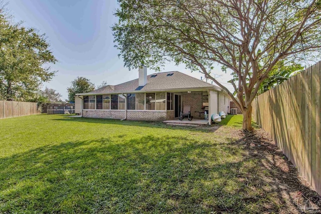 back of house featuring a yard, a patio, and a sunroom