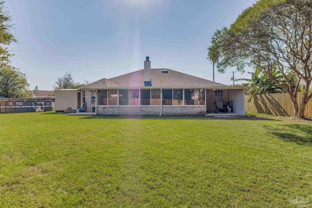 rear view of house with a yard, a patio, and a sunroom