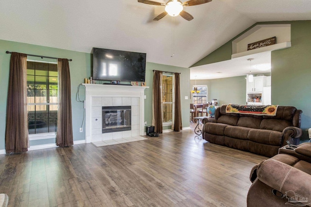 living room with hardwood / wood-style floors, vaulted ceiling, a tile fireplace, and ceiling fan