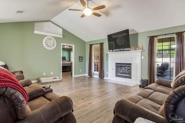 living room featuring lofted ceiling, wood-type flooring, a tile fireplace, a textured ceiling, and ceiling fan