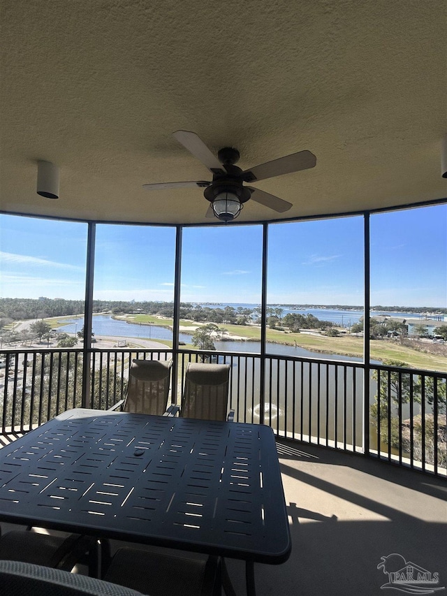 unfurnished sunroom with a ceiling fan and a water view