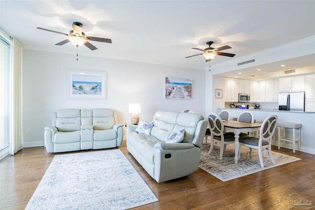 living area with ornamental molding, visible vents, ceiling fan, and wood finished floors